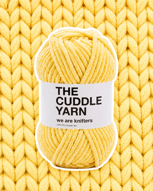 The Cuddle Yarn Yellow skein on matching knit background